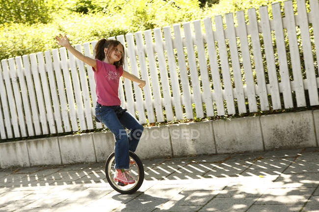Умная девушка катается на одноколесном велосипеде по улице — стоковое фото