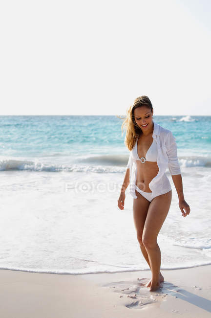 Jovem mulher vestindo biquíni branco na praia — Fotografia de Stock