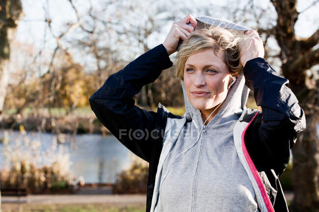 Mujer adulta media ajustando la capucha al aire libre - foto de stock