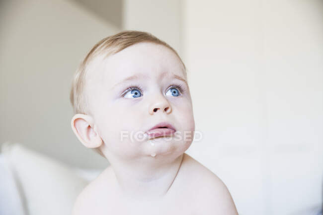Porträt eines blauäugigen dribbelnden Jungen, der vom Bett aufblickt — Stockfoto