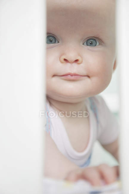 Retrato de la niña mirando a través de las barras en la cuna - foto de stock