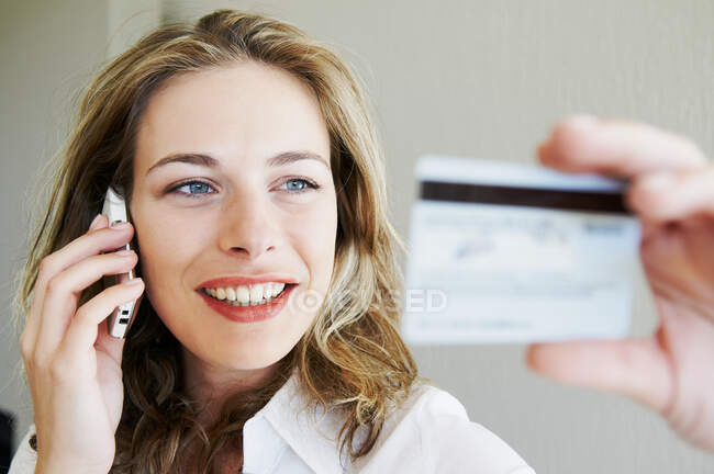 Donna al telefono, guardando la carta di credito — Foto stock