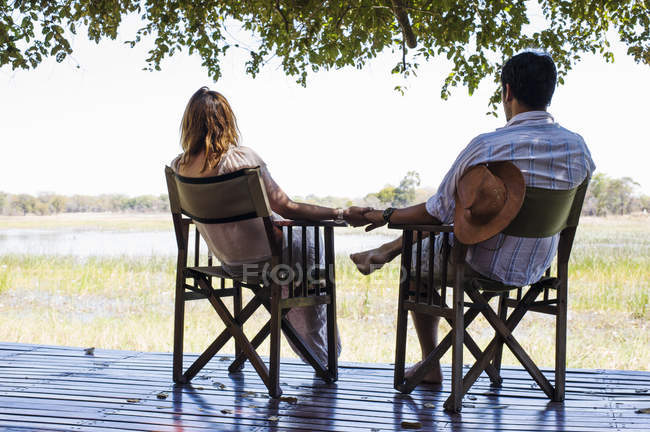Romantic couple holding hands while sitting at safari lodge — Stock Photo