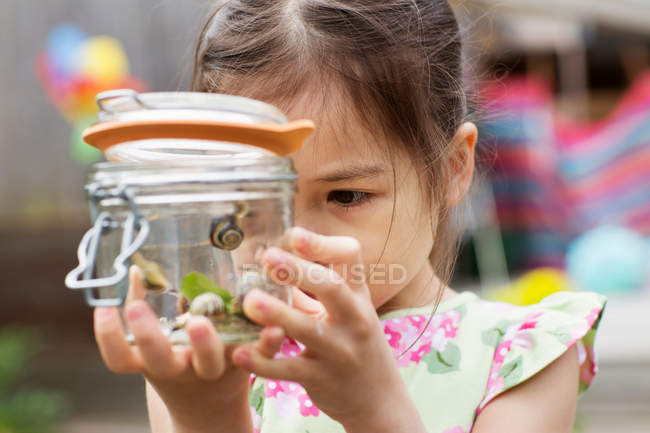Chica joven estudiando tarro de caracoles - foto de stock
