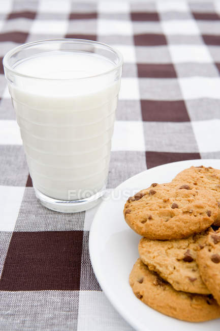 Biscuits et lait sur tissu damier — Photo de stock