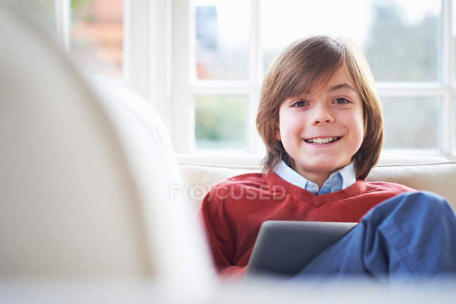 Niño usando tableta digital en el sofá - foto de stock