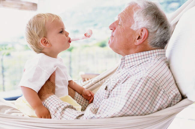 Abuelo con nieto en una hamaca - foto de stock