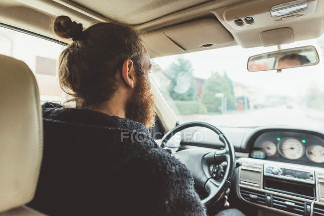 Sobre a vista do ombro do homem barbudo dirigindo um carro — Fotografia de Stock