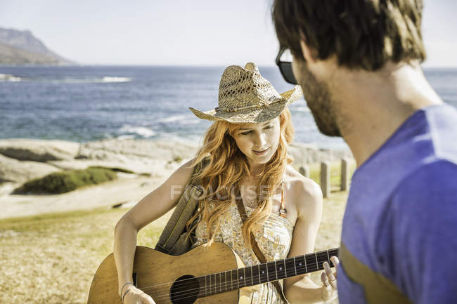 Mid adult couple on coast playing guitar, Cape Town, South Africa — Stock Photo