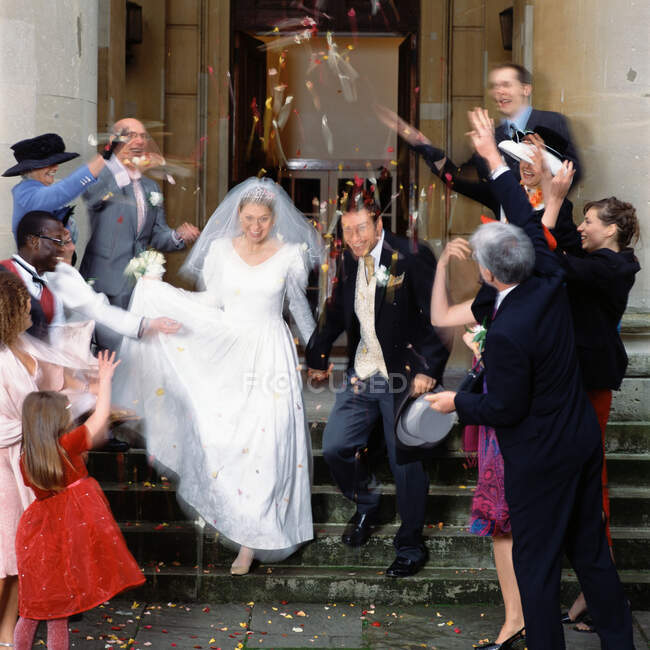 Famille et amis jettent des confettis aux jeunes mariés — Photo de stock