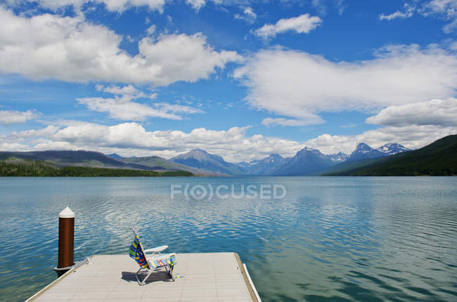 Deckchair on jetty with scenic view of lake and mountain range — Stock Photo