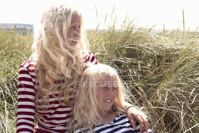 Portrait de deux sœurs assises dans l'herbe haute — Photo de stock