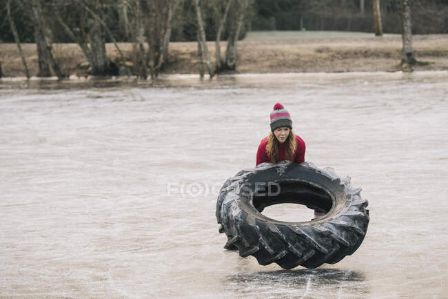 Frau kippt Reifen auf zugefrorenem See — Stockfoto