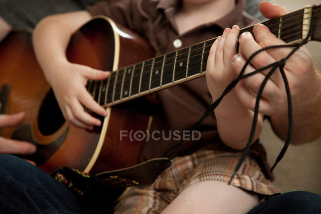 Image recadrée de Garçon et père jouant de la guitare — Photo de stock