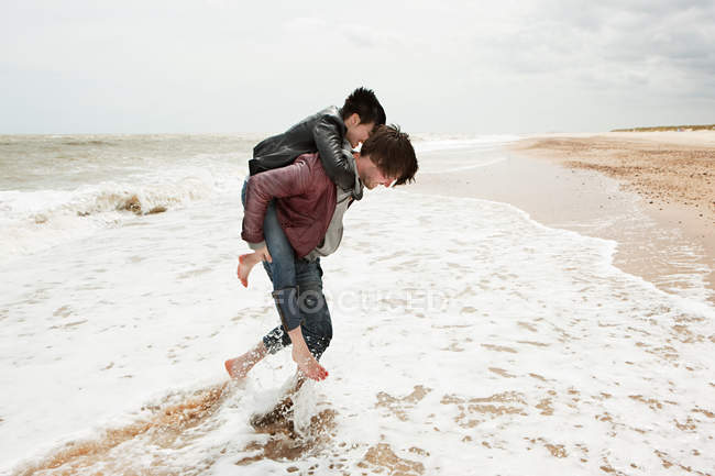 Mann gibt Freundin huckepack im Meer — Stockfoto