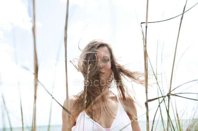 Junge Frau im Gras mit zerzausten Haaren — Stockfoto