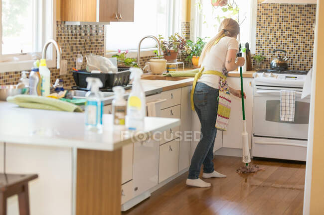 Mujer joven fregando con productos de limpieza verde - foto de stock