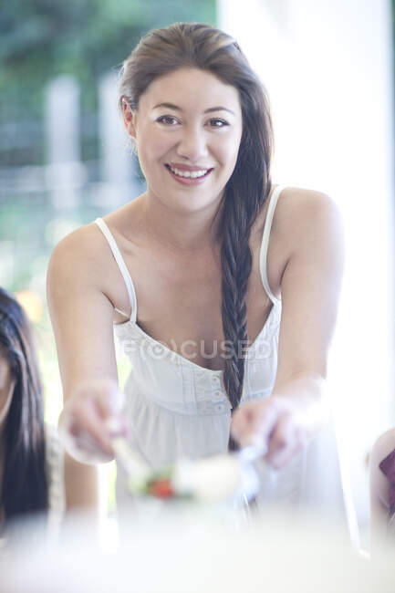 Portrait of young woman serving meal to friends — Stock Photo