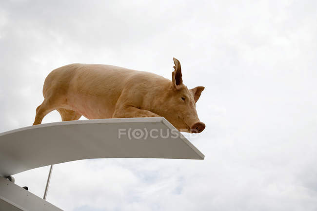 Pig sculpture on diving board with cloudy sky — Stock Photo