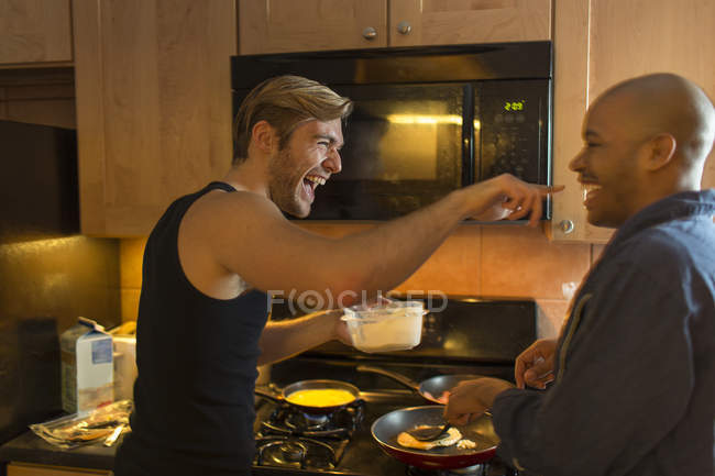 Casal masculino na cozinha, brincando, fazendo café da manhã — Fotografia de Stock