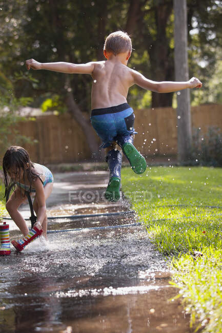 Niño y niña jugando con agua en un río - foto de stock