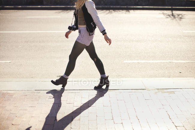 Young woman with camera walking down street — Stock Photo
