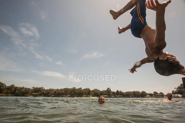 Menino fazendo backflip em água — Fotografia de Stock