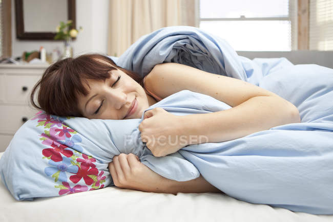 Jeune femme au lit les yeux fermés — Photo de stock