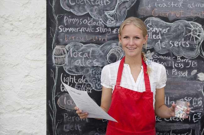Waitress holding jar of chalk and menu in cafe — Stock Photo