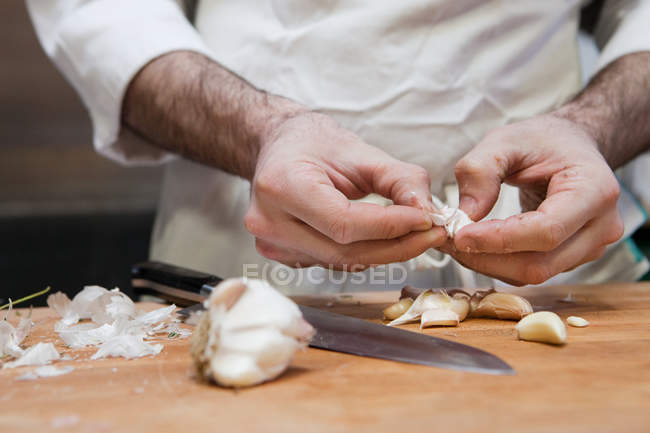 Masculino chef mãos descascando alho — Fotografia de Stock