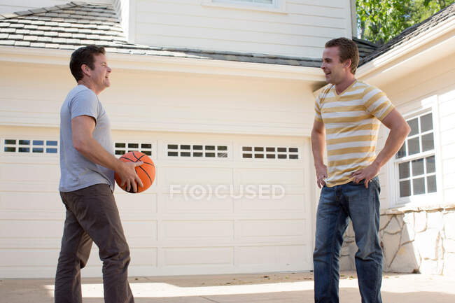 Père tenant basket-ball avec fils adulte — Photo de stock