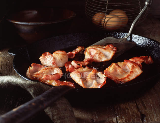 Rashers de bacon na frigideira vintage e ovos na cesta de arame — Fotografia de Stock