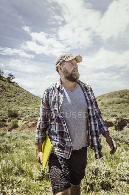 Uomo che trasporta laptop giallo in paesaggio, Bridger, Montana, Stati Uniti d'America — Foto stock