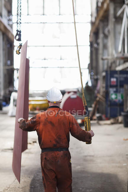 Rear view of worker using winch in shipyard workshop — Stock Photo