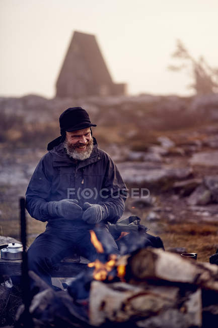 Escursionista felice seduto accanto al falò al campo, Lapponia, Finlandia — Foto stock