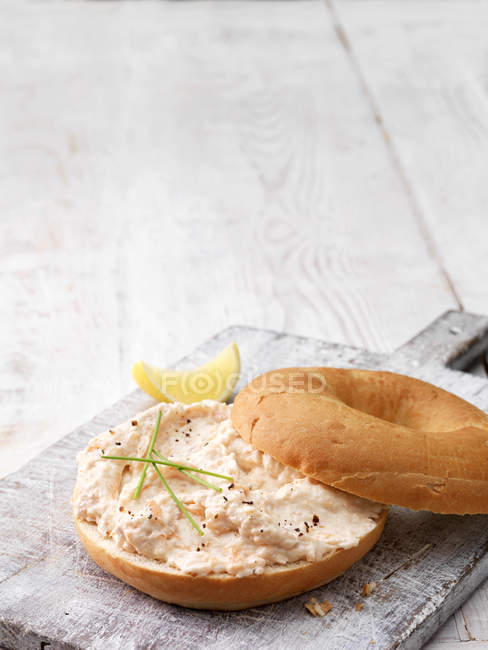 Копчений лосось і м'який сирний багель, прикрашений цибулею, чорним перцем і лимонним клином — стокове фото