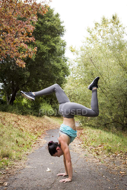 Formation de femme adulte moyenne, faisant handstand dans le parc — Photo de stock