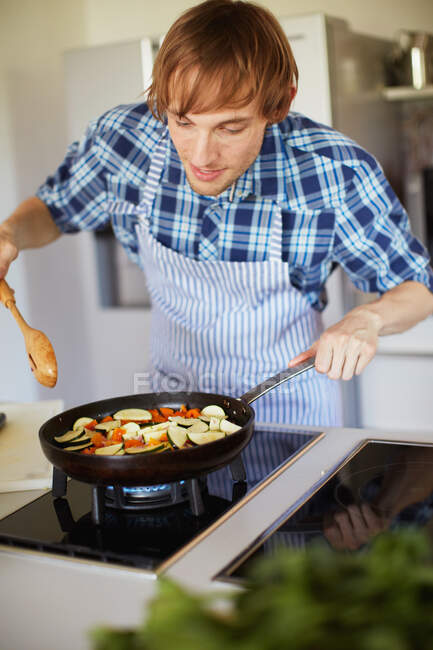 Homme frire des légumes dans la cuisine — Photo de stock
