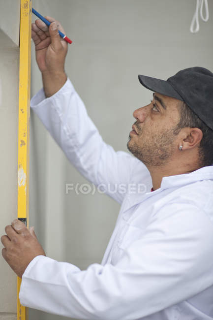 Side view of builder marking wall with pencil — Stock Photo