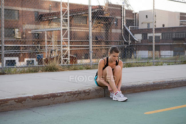 Женщина-бегунья сидит на тротуаре — стоковое фото