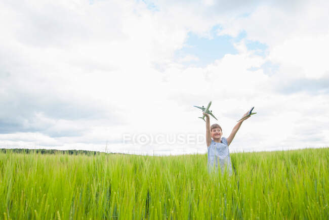 Menina brincando com aviões de brinquedo no campo — Fotografia de Stock