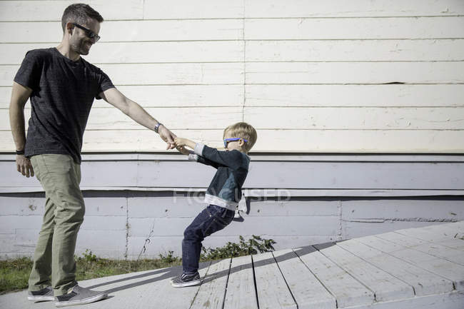 Junge zieht Vater auf Holzrampe — Stockfoto