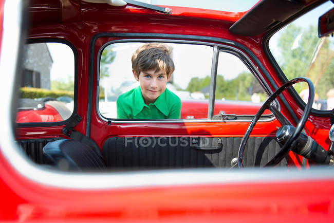 Boy looking through window of vintage automobile — Stock Photo