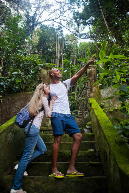 Couple looking away on steps in jungle — Stock Photo