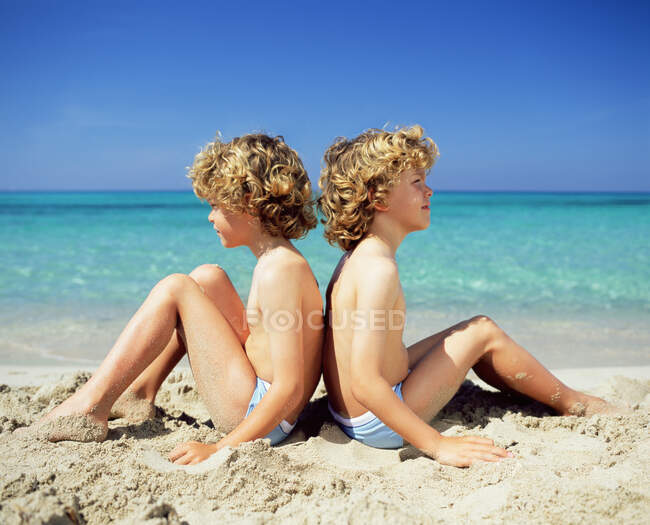 Zwillingsjungen sitzen am Strand — Stockfoto