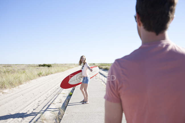 Couple with surfboard on coastal path, Breezy Point, Queens, New York, USA — Stock Photo