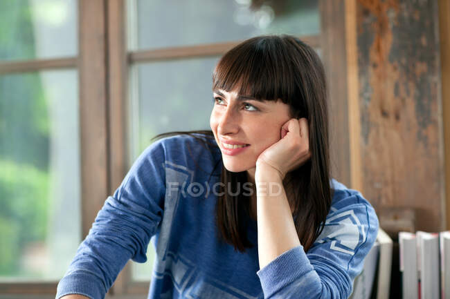 Porträt einer brünetten Frau, die mit der Hand am Kinn lächelt — Stockfoto