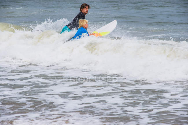 Padre e hijo en el mar con tablas de surf, preparándose para surfear - foto de stock