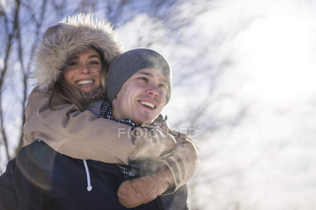 Молодая женщина с руками вокруг мужчины во время зимы на открытом воздухе, Монреаль, Квебек, Канада — стоковое фото