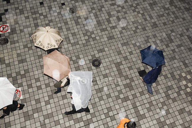 Overhead view of People with umbrellas on pavement — Stock Photo